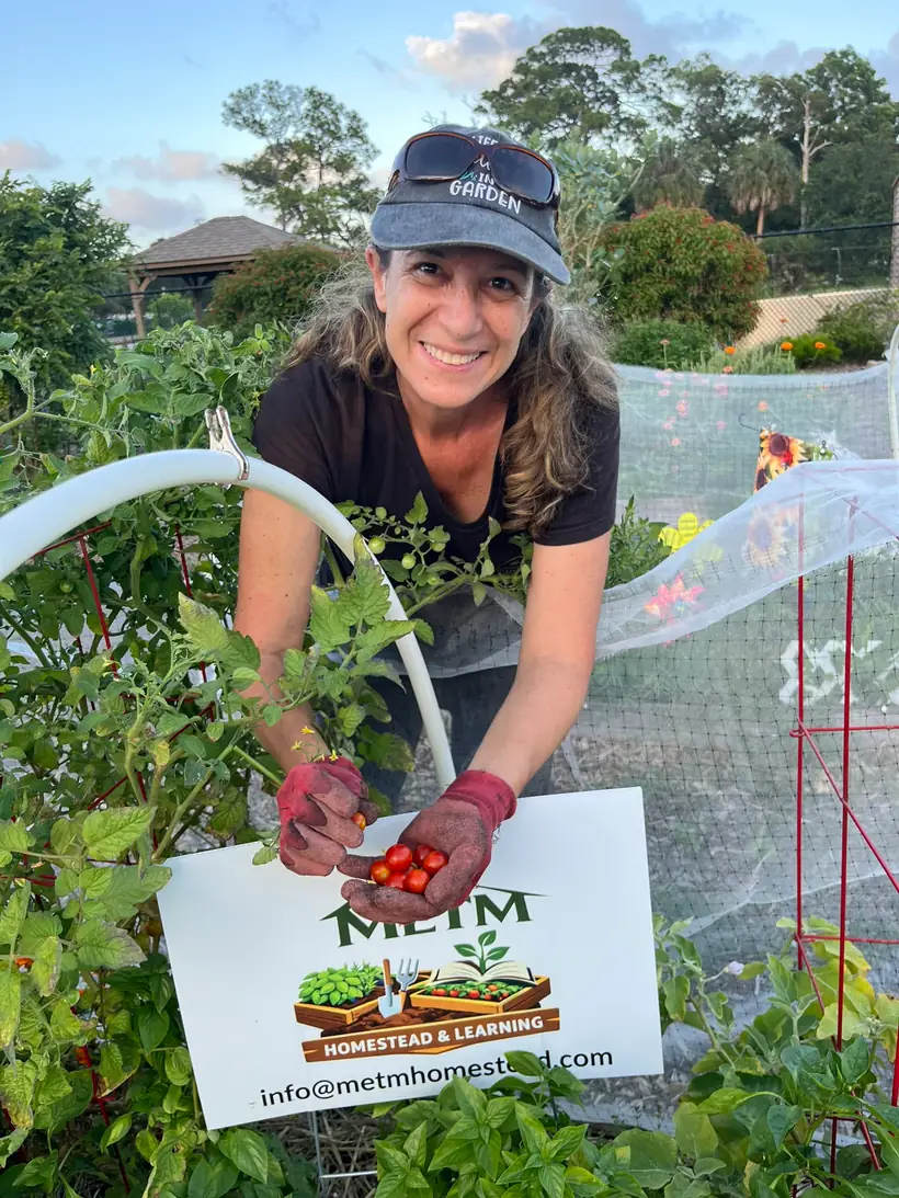 Melanie smiling in the garden with a fresh harvest